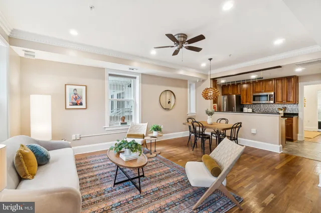 a living room with furniture kitchen view and a large window
