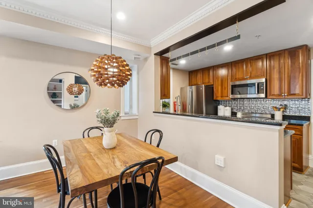 a kitchen with kitchen island granite countertop a stove a sink a dining table and chairs with wooden floor