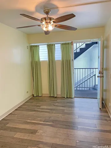 a view of a room with wooden floor fan and windows