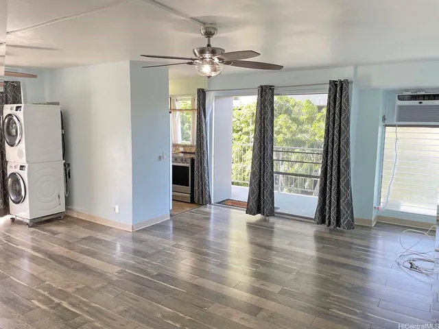 a view of an empty room with a window and wooden floor