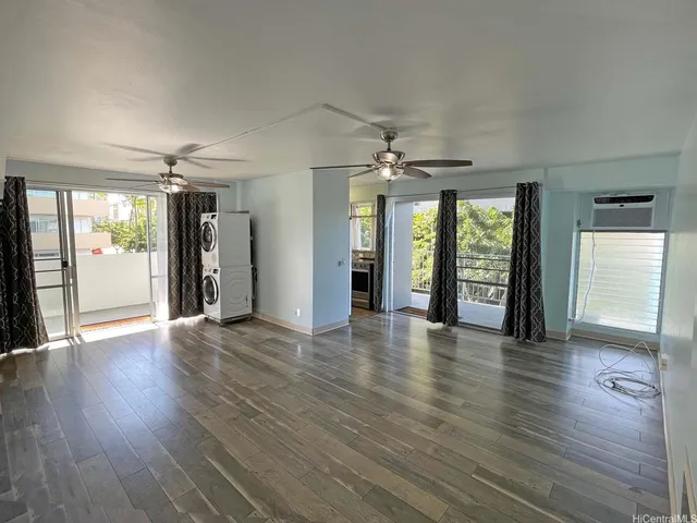 a view of an empty room with window and wooden floor