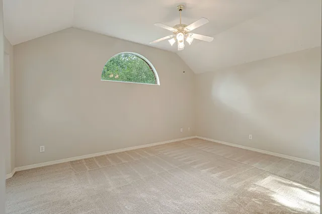 an empty room with a chandelier fan and windows