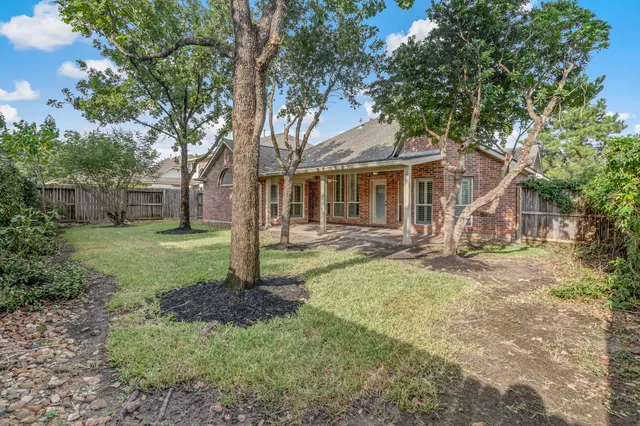 a view of a yard in front of a house with large tree