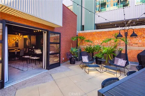 a view of a patio with a table and chairs under an umbrella with a small yard