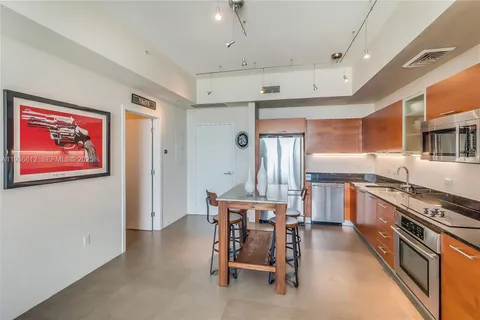 a kitchen with stainless steel appliances a table chairs refrigerator and cabinets