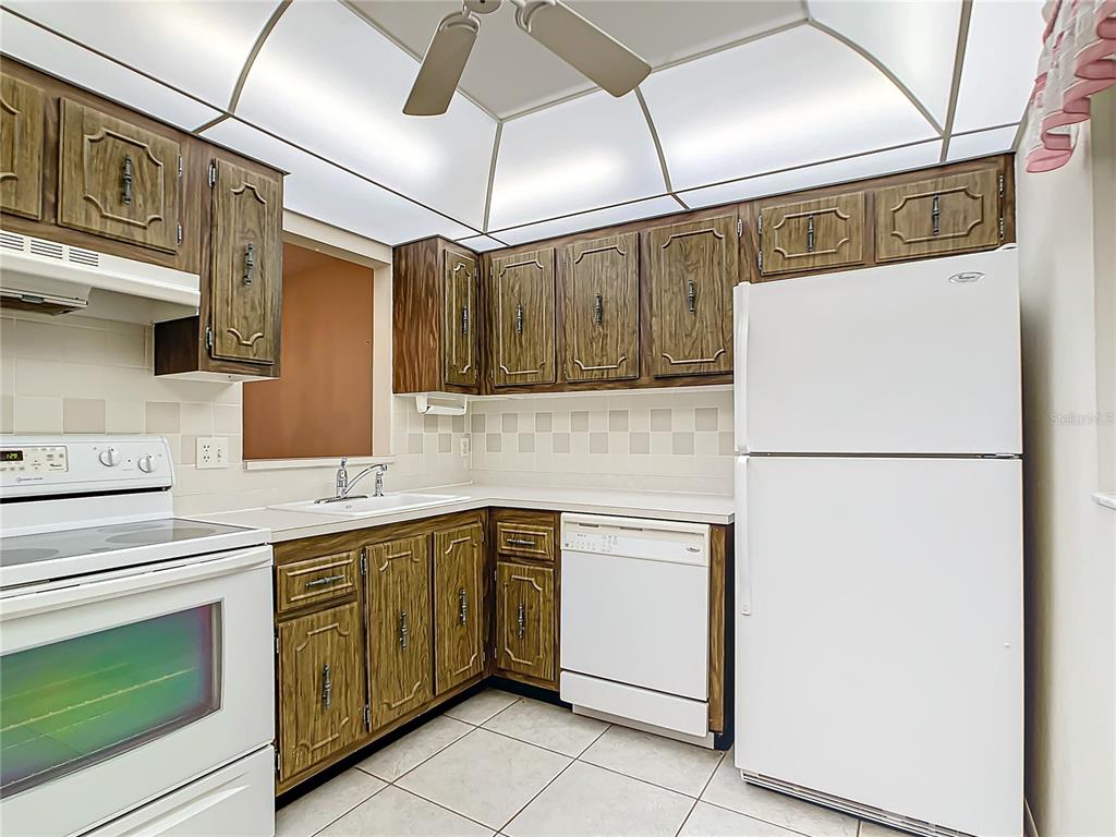 11485 Oakhurst Road, Unit 107 Largo, FL 33774 - Photo 13 of 60 a kitchen with cabinets and white stainless steel appliances