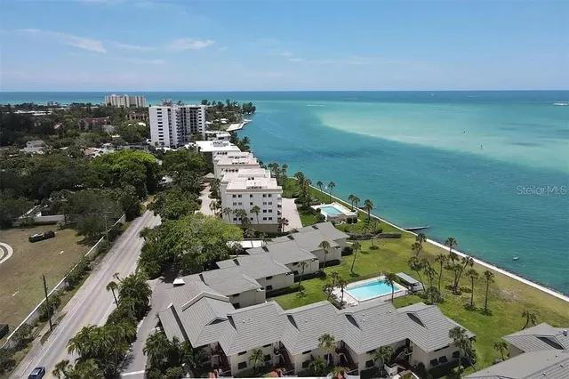 an aerial view of ocean and residential houses with outdoor space