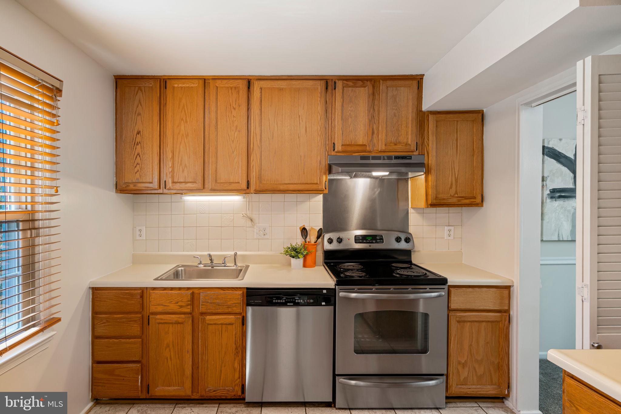 5702 Kirkham Court Springfield, VA 22151 - Photo 7 of 36 a kitchen with stainless steel appliances granite countertop wooden cabinets stove top oven and sink