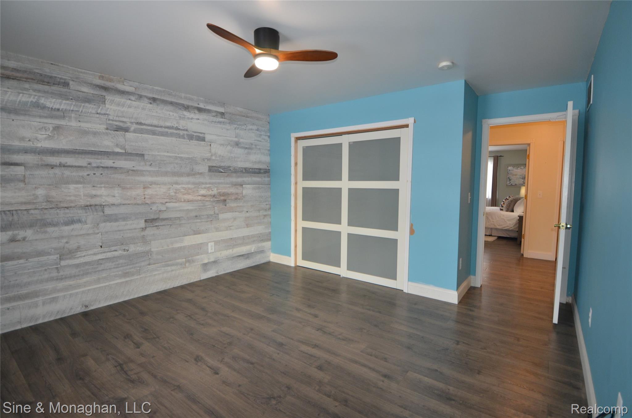 76152 Burman Road Richmond, MI 48062 - Photo 46 of 75 Unfurnished room featuring wooden walls, dark wood-style flooring, a ceiling fan, and an accent wall