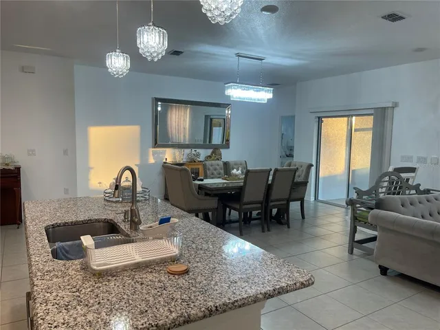 a view of a dining room and livingroom with furniture wooden floor a rug a fireplace and a chandelier
