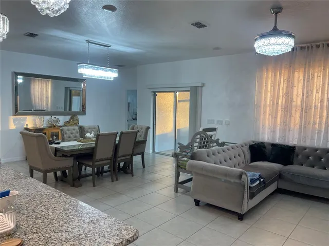 a living room with furniture a chandelier and a dining table