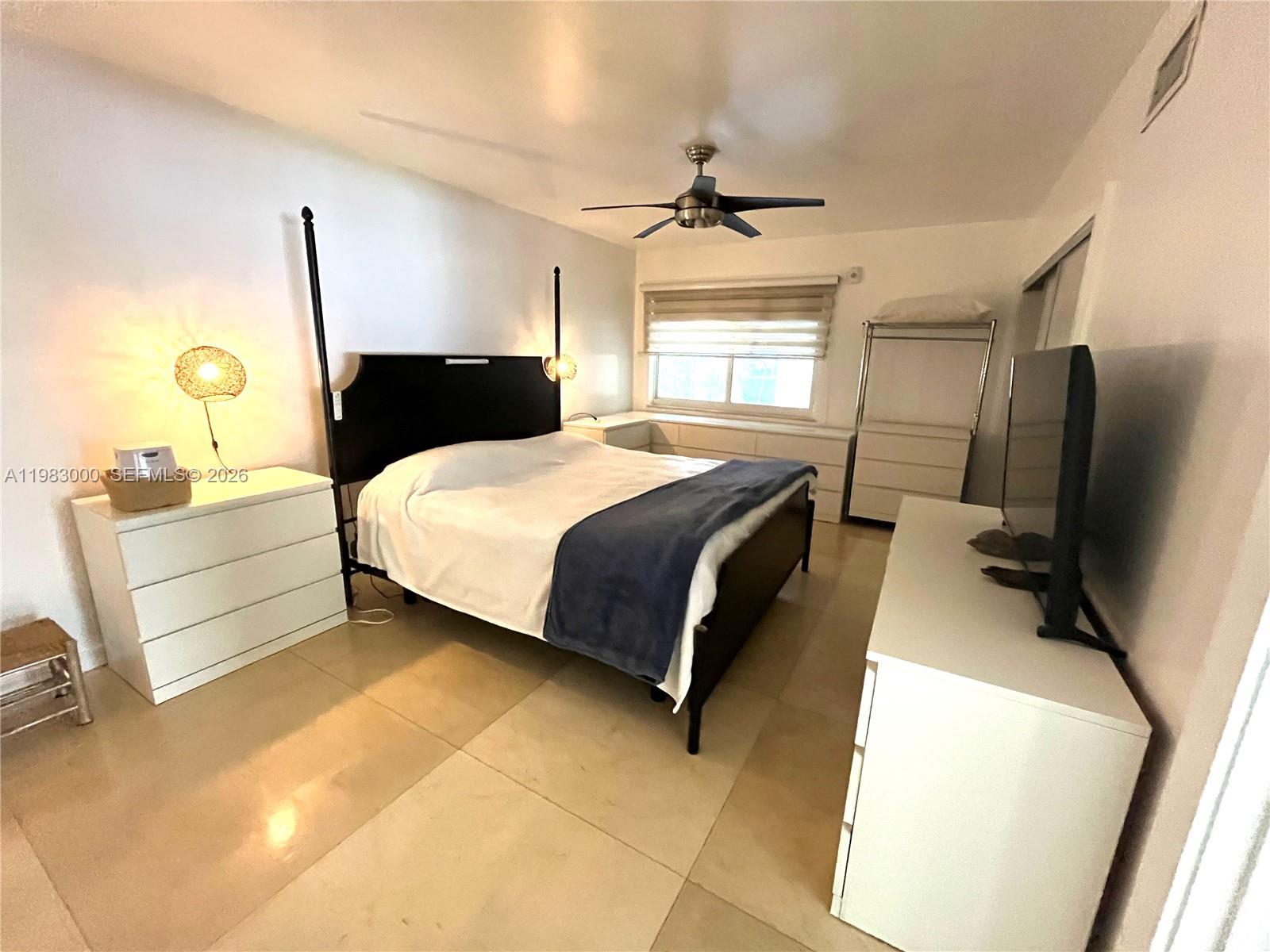 10190 Collins Avenue, Unit 106 Bal Harbour, FL 33154 - Photo 13 of 21 a bedroom with a bed tv and a mirror