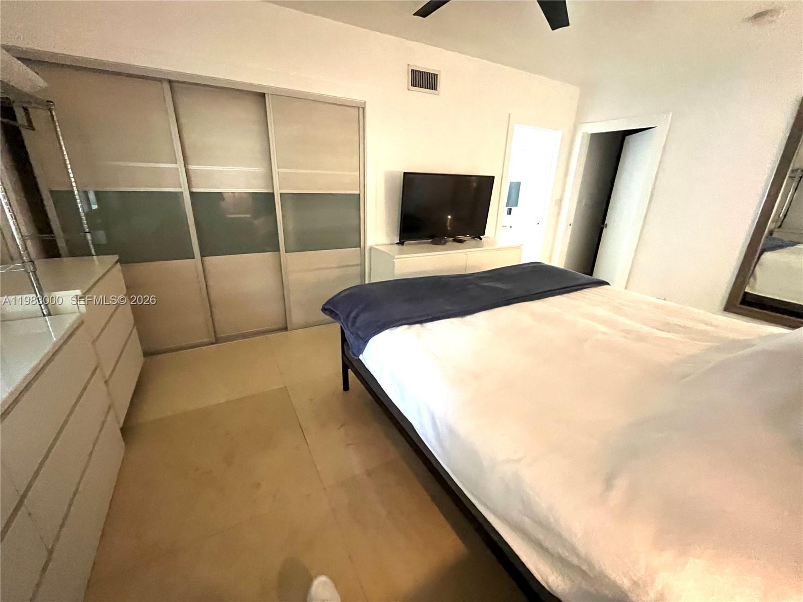 10190 Collins Avenue, Unit 106 Bal Harbour, FL 33154 - Photo 14 of 21 a bedroom with a bed and a flat screen tv