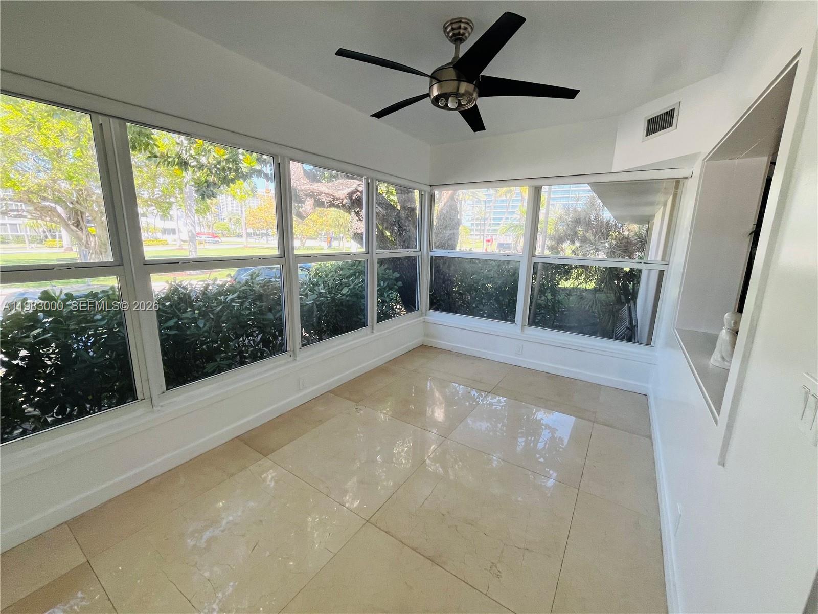 10190 Collins Avenue, Unit 106 Bal Harbour, FL 33154 - Photo 18 of 21 a view of an empty room with a floor to ceiling windows and a ceiling fan