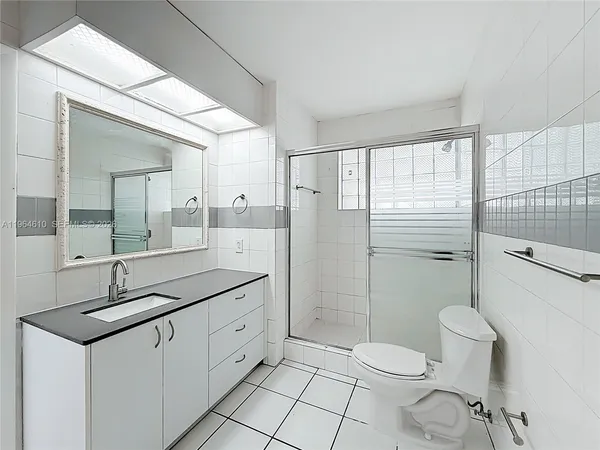 a spacious bathroom with a granite countertop sink toilet a mirror and shower