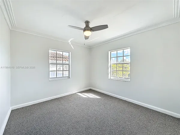 an empty room with windows and fan