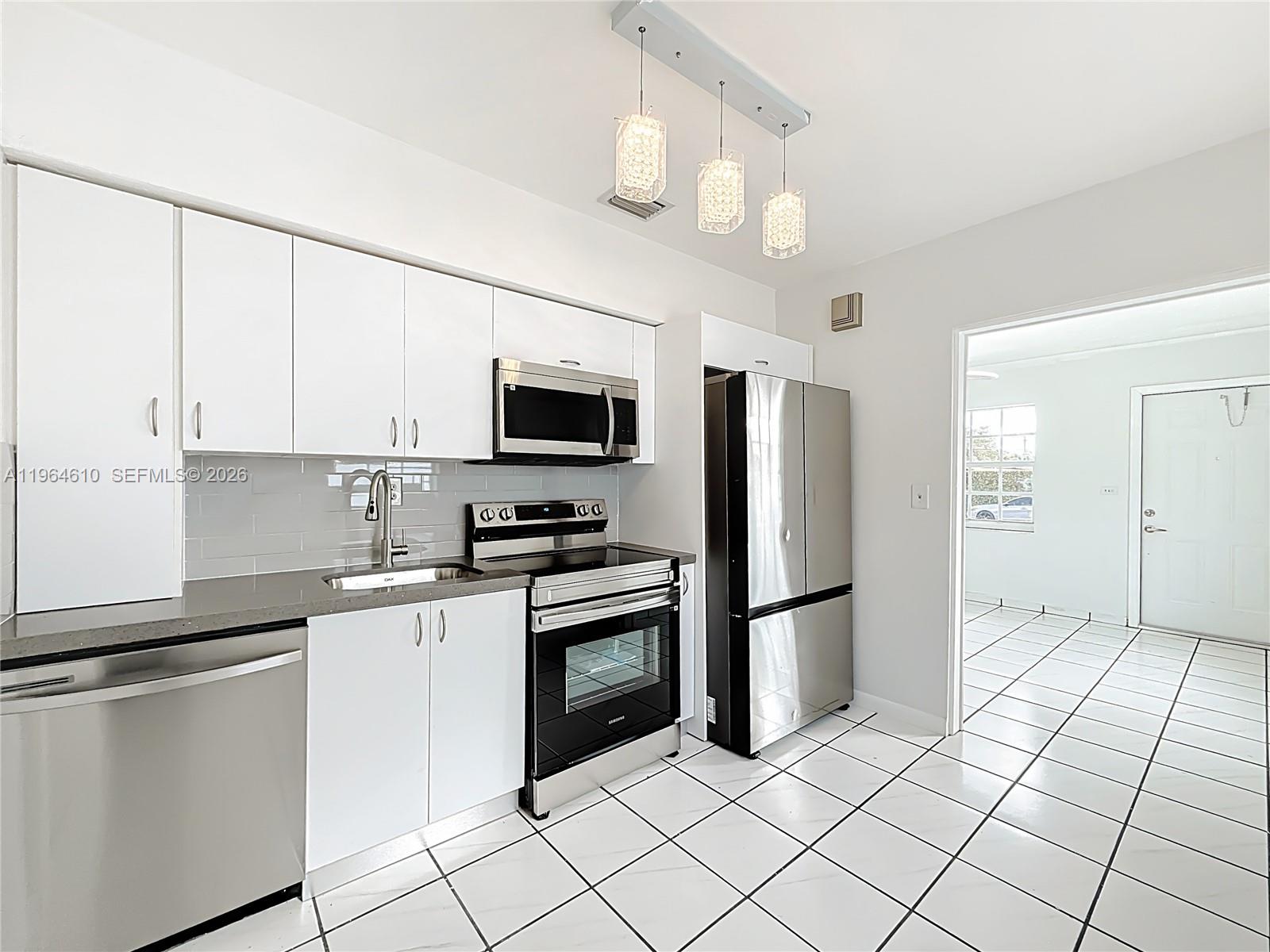 6819 Southwest 25th Street Miami, FL 33155 - Photo 7 of 25 a kitchen with stainless steel appliances granite countertop a refrigerator oven a sink dishwasher and white cabinets with wooden floor