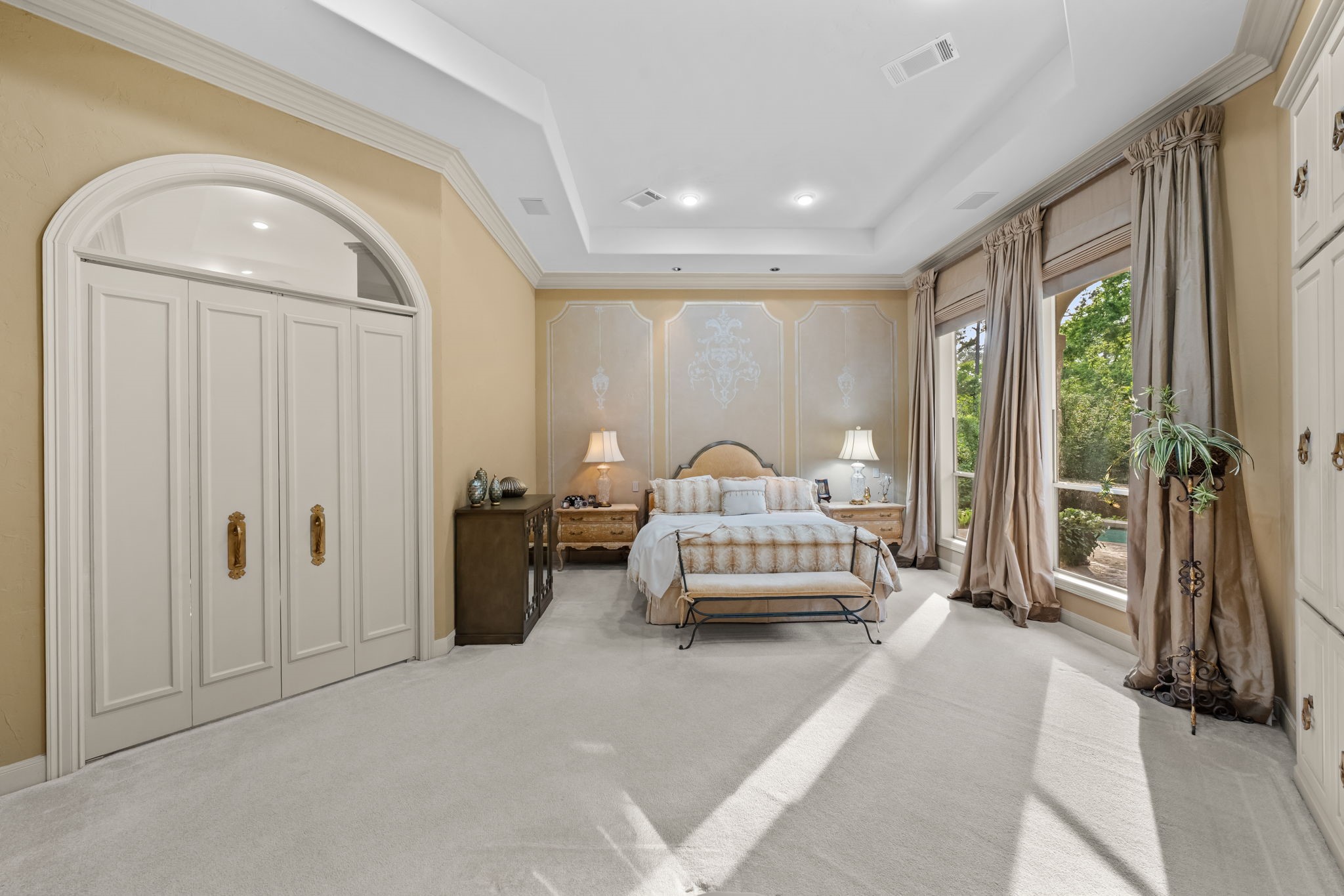 6 Mott Lane Houston, TX 77024 - Photo 17 of 50 Spacious and serene primary suite featuring a tray ceiling, elegant wall detailing, and abundant natural light