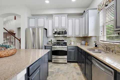 a kitchen with stainless steel appliances granite countertop a stove a sink and a refrigerator