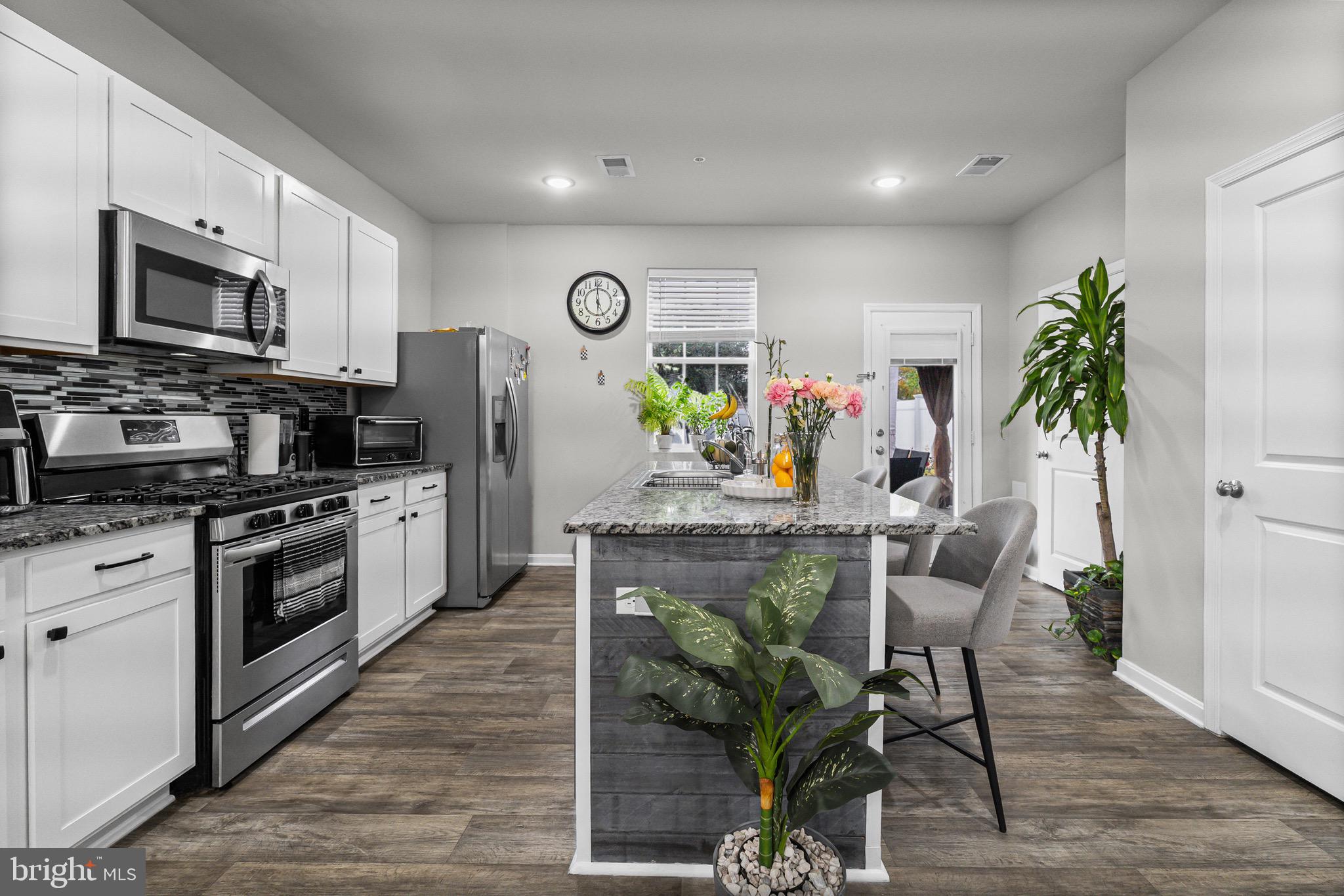 1901 Graymount Way Edgewood, MD 21040 - Photo 5 of 24 a kitchen with granite countertop a refrigerator stove a sink dishwasher and white cabinets with wooden floor