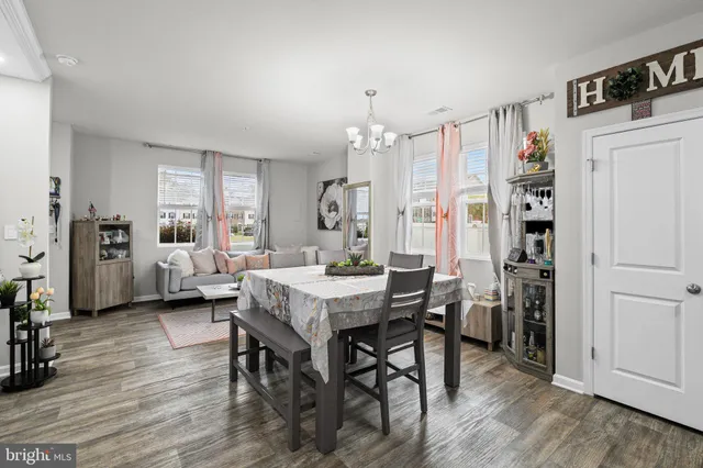 a kitchen with stainless steel appliances granite countertop a dining table chairs refrigerator and microwave