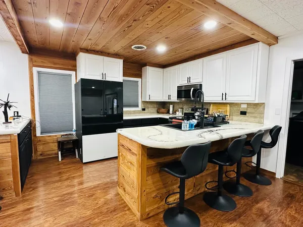 a kitchen with granite countertop a table chairs microwave and cabinets
