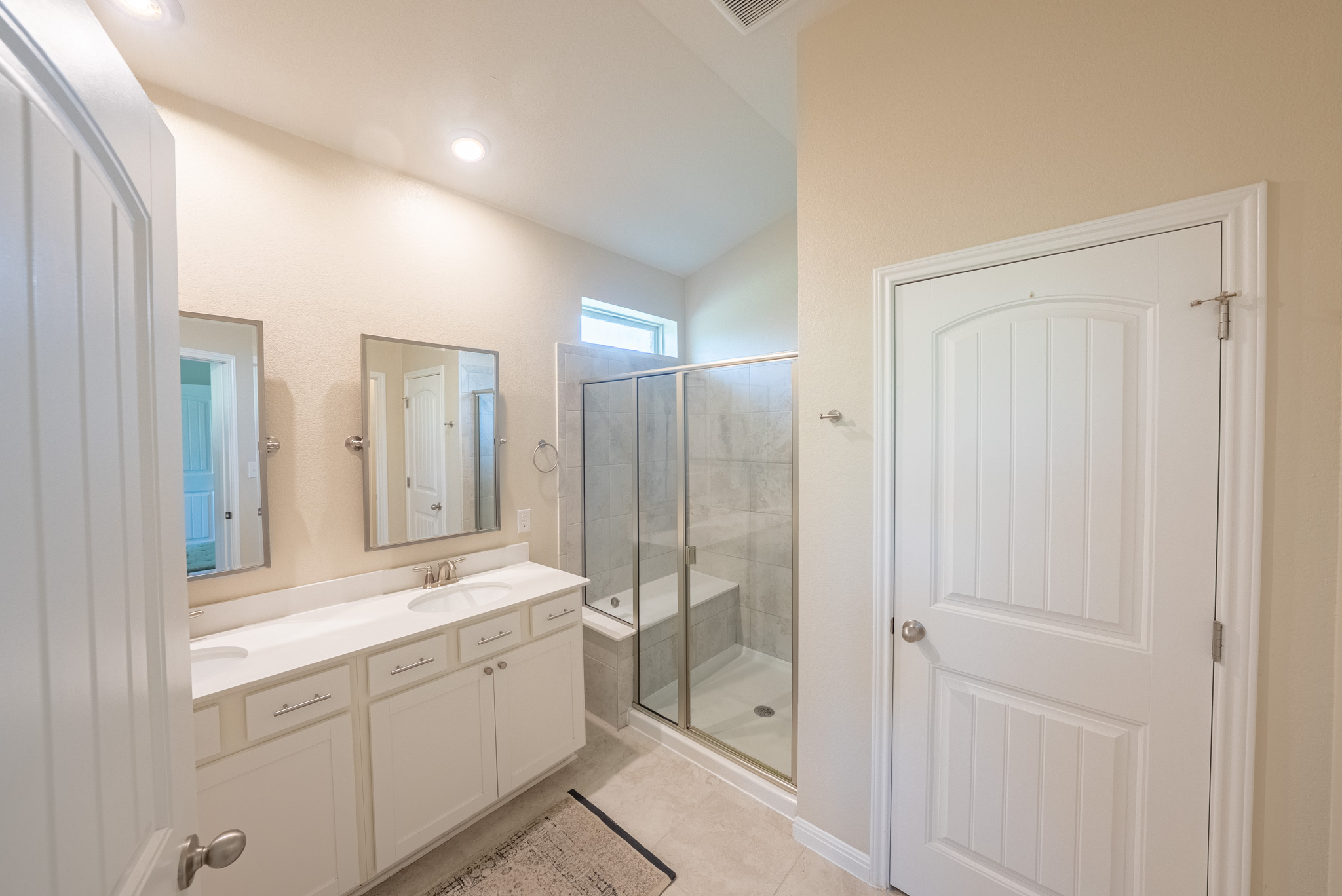 2508 Hat Bender Loop Round Rock, TX 78664 - Photo 12 of 22 Bathroom featuring a dual vanity with undermount sinks, a walk-in shower with a glass enclosure and built-in bench, and light-toned tile flooring