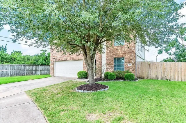 a front view of a house with yard and tree