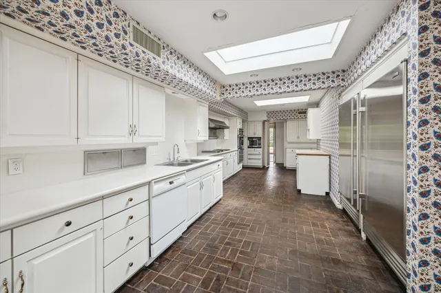 a large white kitchen with a sink and refrigerator