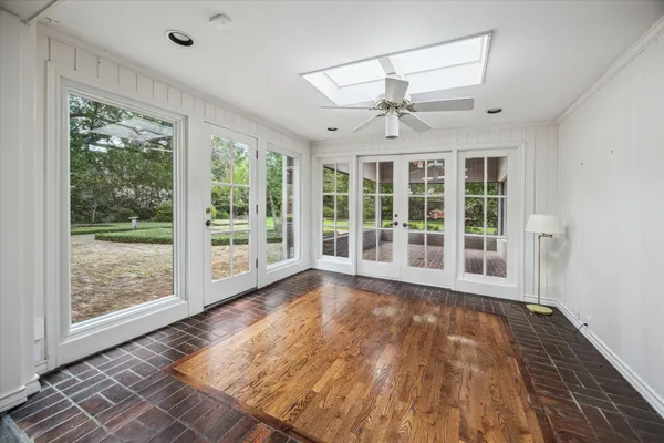 a view of an empty room with wooden floor and a window