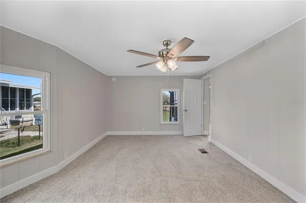an empty room with windows and fan