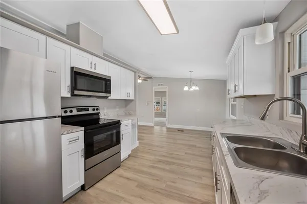 a kitchen with granite countertop a sink wooden cabinets and stainless steel appliances