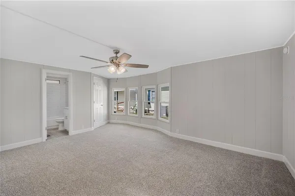 a view of a livingroom with a chandelier fan and windows