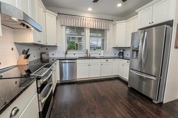 a kitchen with stainless steel appliances white cabinets and a wooden floors
