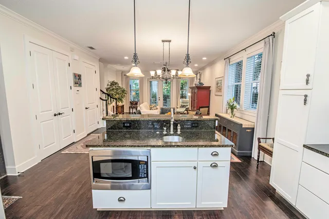 a kitchen with stainless steel appliances granite countertop a stove a sink and a wooden floor