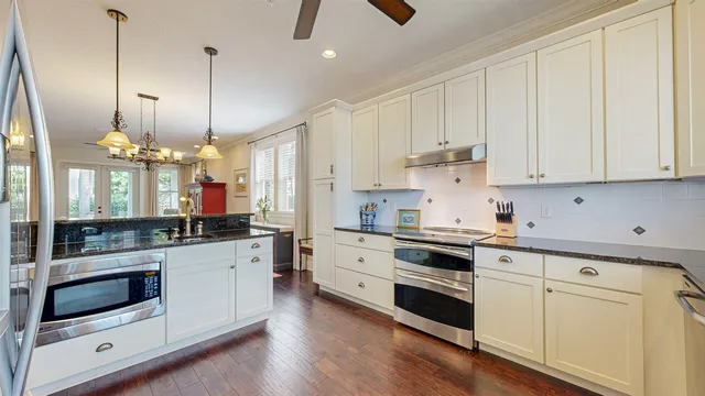 a kitchen with stainless steel appliances white cabinets and a wooden floors