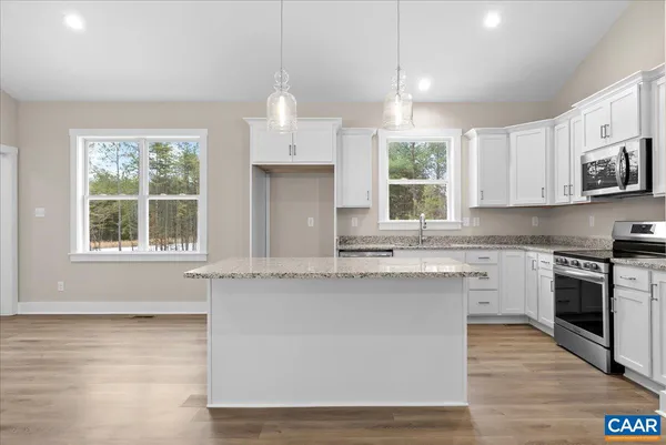 a kitchen with stainless steel appliances granite countertop a stove a sink dishwasher a refrigerator and a microwave oven with wooden floor