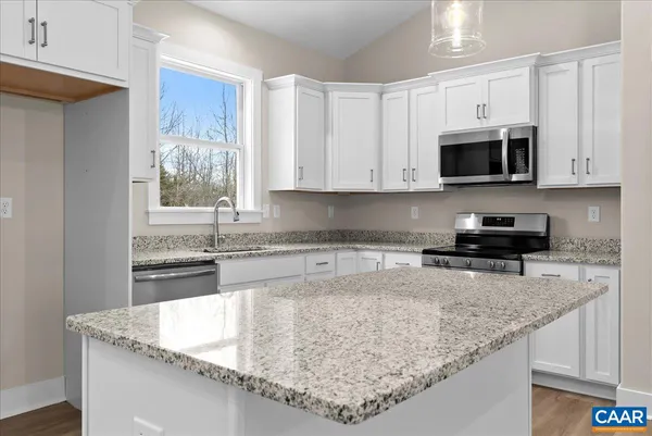 a kitchen with granite countertop a sink a stove and cabinets