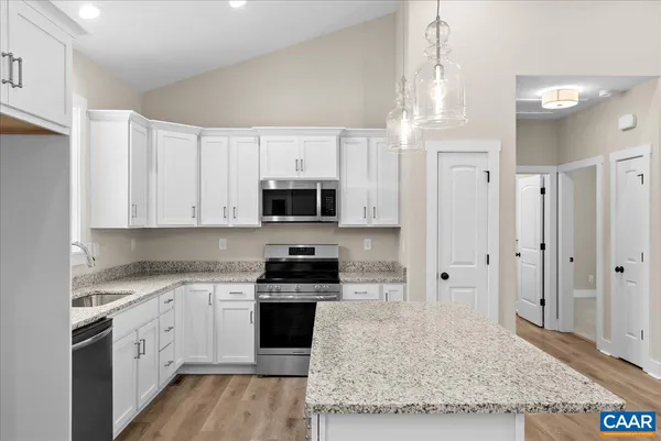 a kitchen with granite countertop a sink stainless steel appliances and white cabinets