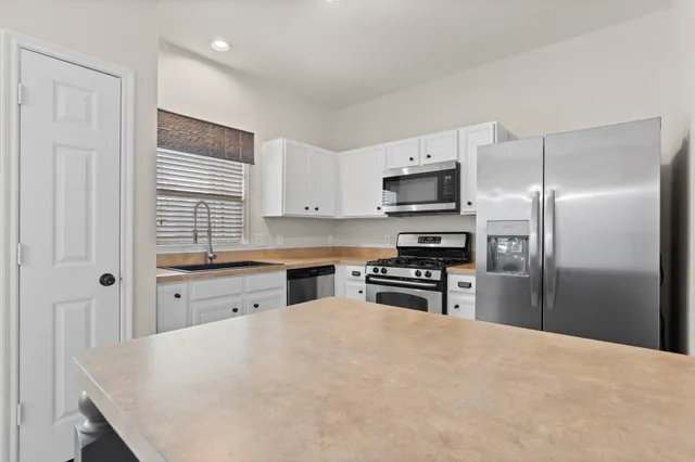 a kitchen with granite countertop a refrigerator stove top oven and sink