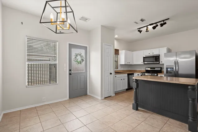 a kitchen with stainless steel appliances granite countertop a refrigerator a sink dishwasher a stove and white cabinets