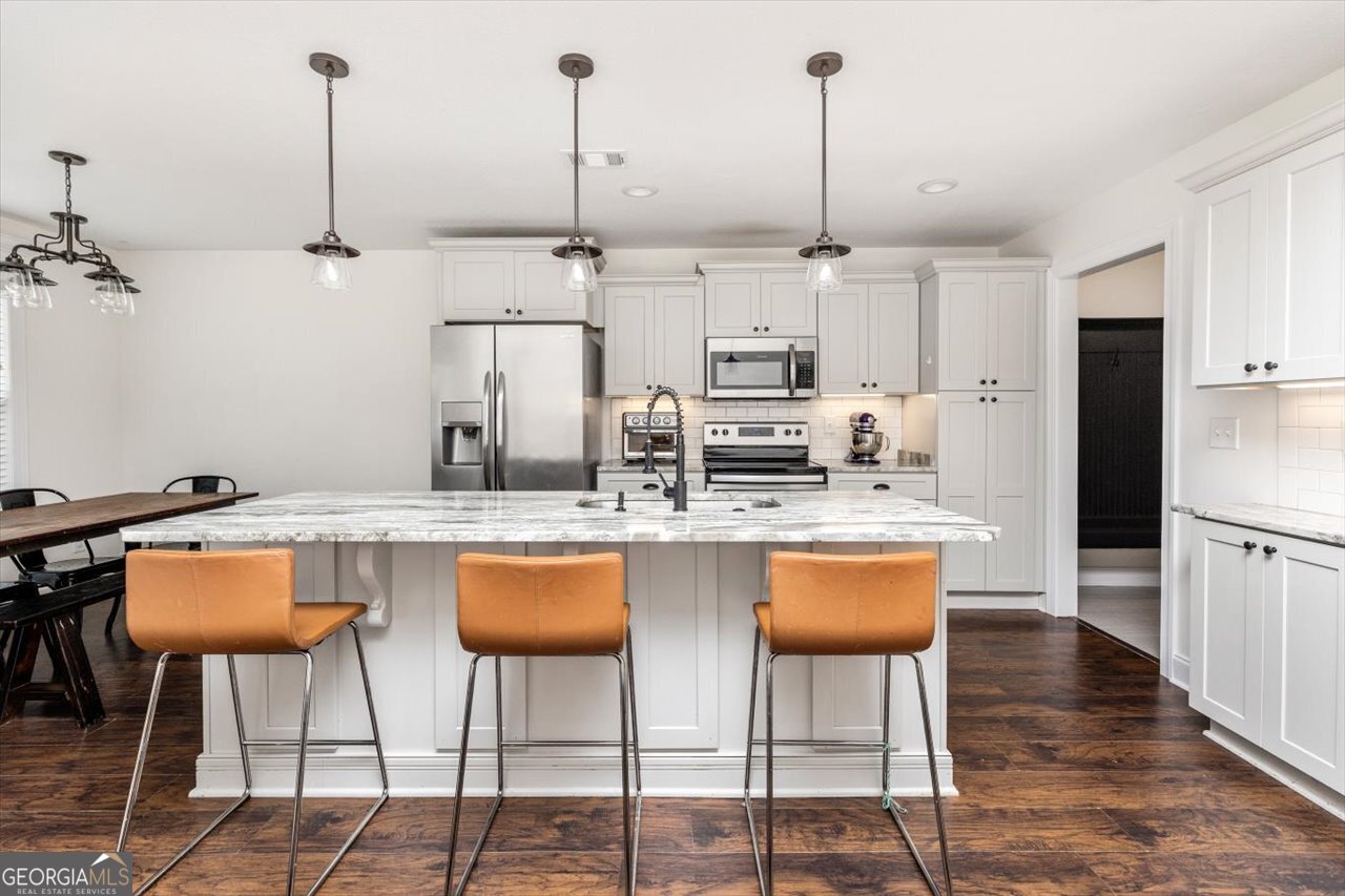 207 Kendall Court Perry, GA 31069 - Photo 13 of 45 a kitchen with stainless steel appliances kitchen island granite countertop a dining table chairs and white cabinets