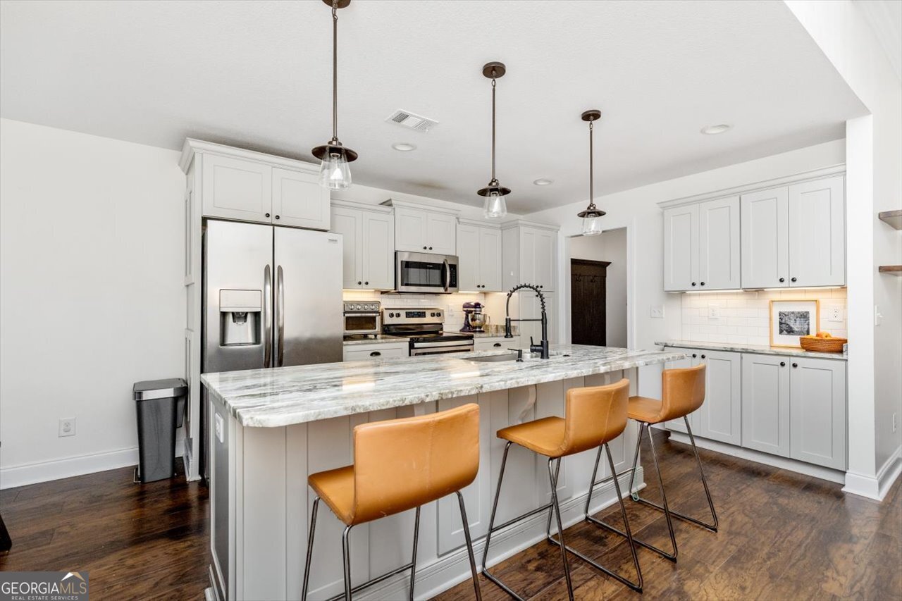 207 Kendall Court Perry, GA 31069 - Photo 14 of 45 a kitchen with stainless steel appliances granite countertop a sink a stove a refrigerator and chairs with wooden floor