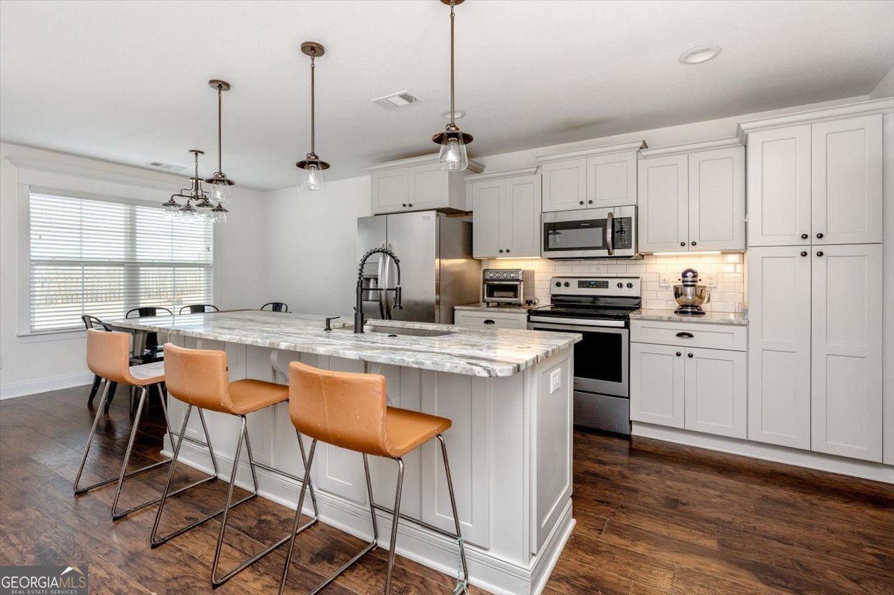 207 Kendall Court Perry, GA 31069 - Photo 15 of 45 a kitchen with stainless steel appliances granite countertop a sink a stove a refrigerator cabinets and chairs