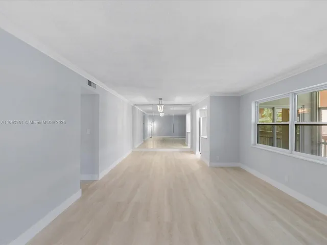 a view of an empty room with a window and wooden floor