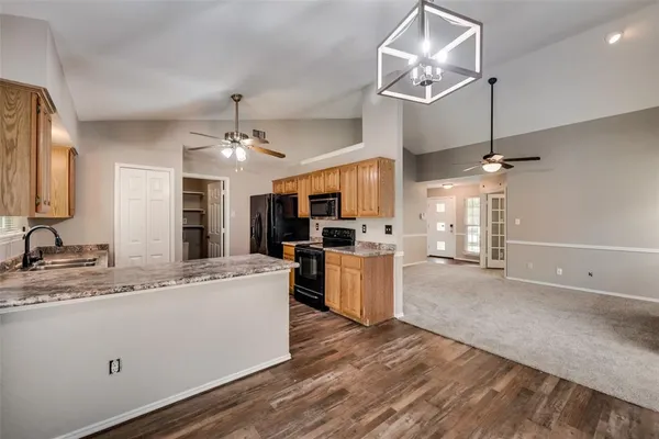 a large kitchen with a sink stainless steel appliances and chandelier