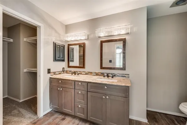 a bathroom with a double vanity sink and mirror with toilet