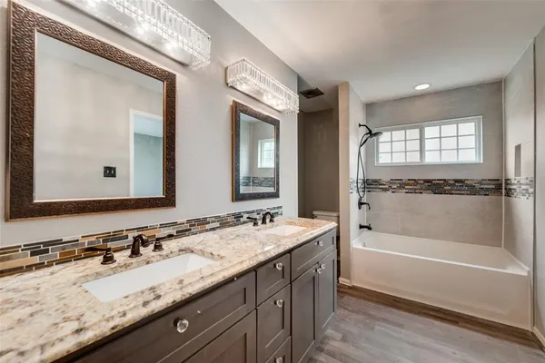 a bathroom with a granite countertop tub sink and mirror