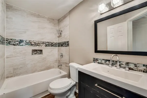 a bathroom with a bathtub shower sink vanity mirror and toilet