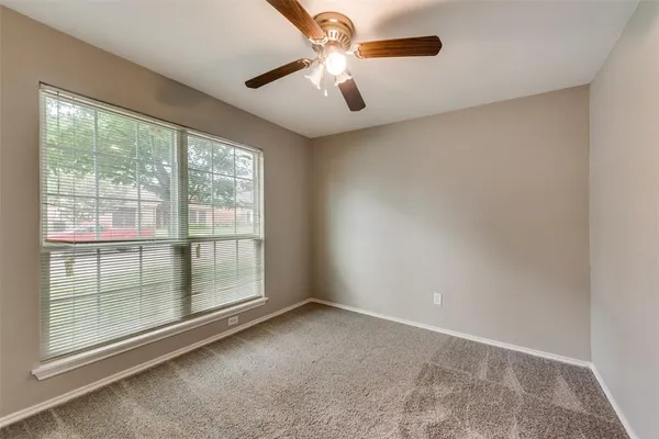 en empty room with windows and ceiling fan